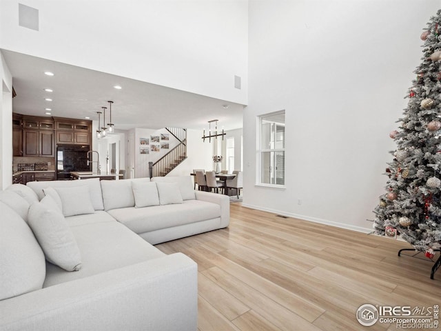 living room featuring a towering ceiling, light hardwood / wood-style floors, and a notable chandelier