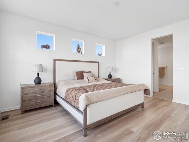 bedroom with light wood-type flooring and ensuite bath