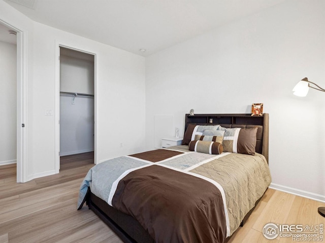 bedroom featuring a spacious closet, a closet, and light hardwood / wood-style flooring