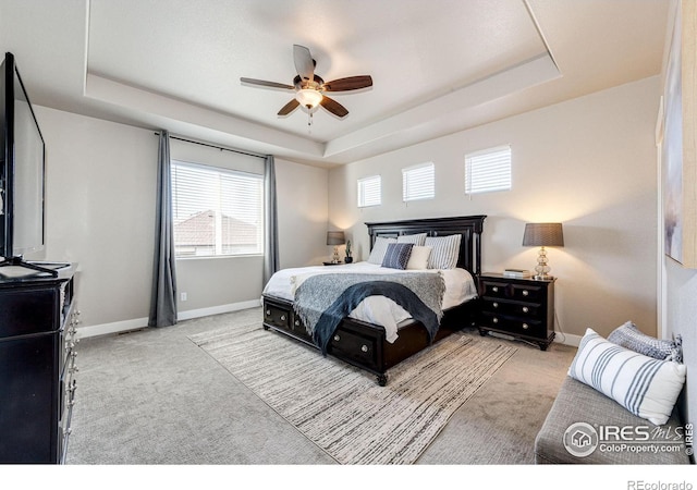 carpeted bedroom featuring a raised ceiling and ceiling fan