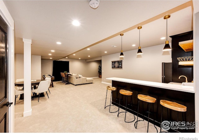 bar featuring stainless steel refrigerator, decorative light fixtures, sink, and light carpet