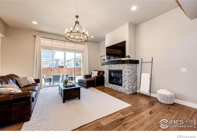 living room with a notable chandelier, hardwood / wood-style flooring, and a fireplace