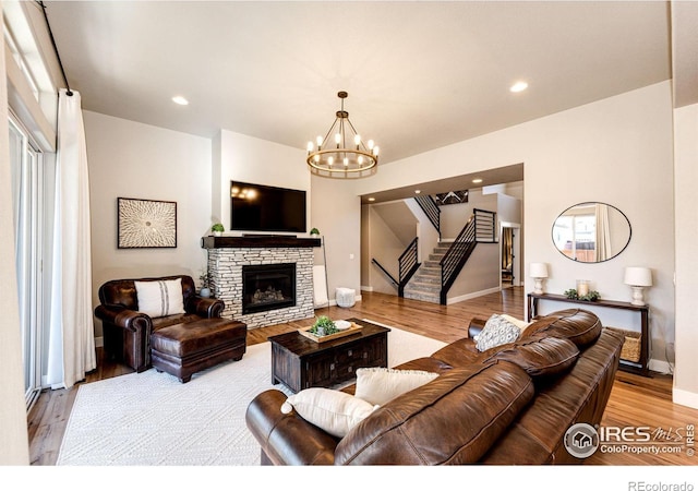 living room with a stone fireplace, an inviting chandelier, and light hardwood / wood-style flooring