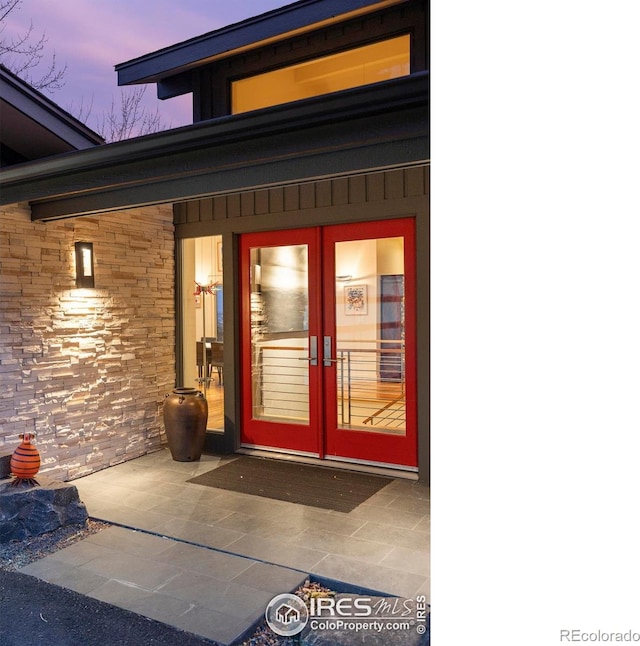 exterior entry at dusk with french doors and stone siding