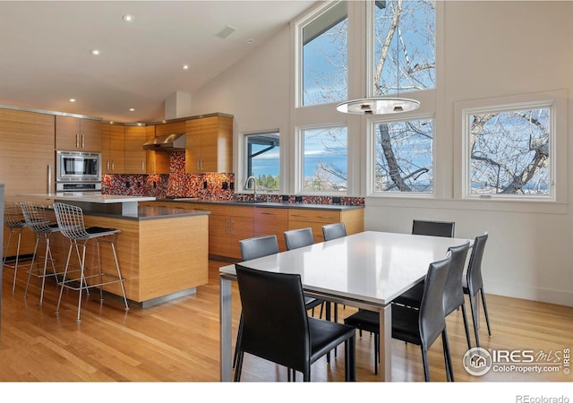 dining space with recessed lighting, light wood-type flooring, baseboards, and a towering ceiling