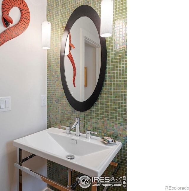 bathroom featuring tile walls, backsplash, and a sink