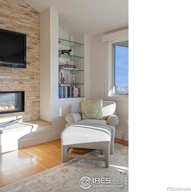 sitting room with baseboards, lofted ceiling, wood finished floors, and a fireplace