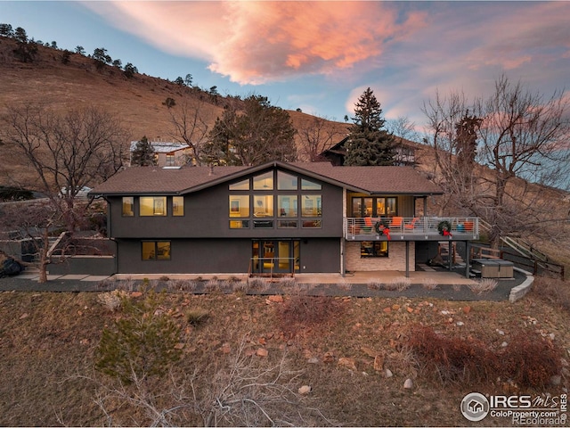 back of property at dusk featuring a deck and a patio area