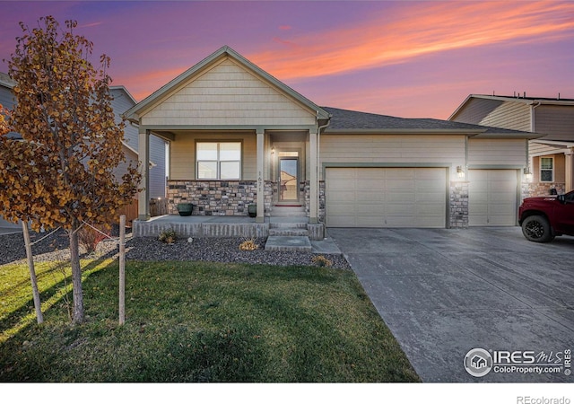 view of front facade with a garage, stone siding, a front yard, and driveway