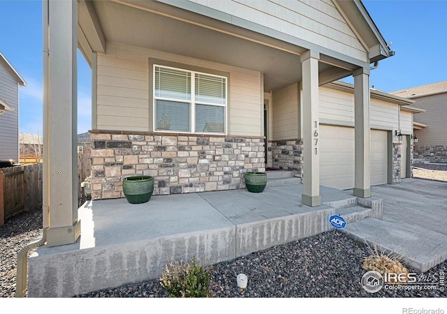 exterior space featuring a garage, stone siding, fence, and a porch