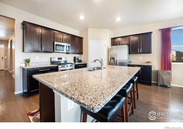 kitchen with an island with sink, a breakfast bar area, appliances with stainless steel finishes, and a sink