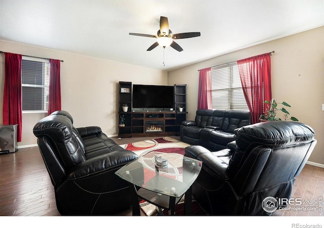 living area featuring a ceiling fan, baseboards, and wood finished floors