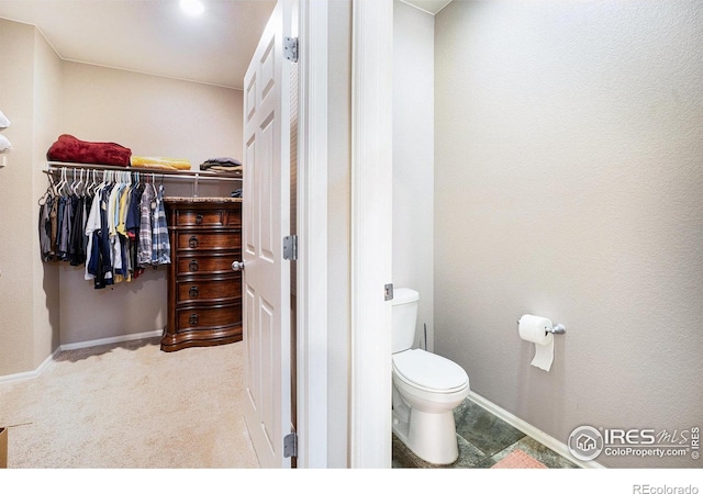 bathroom featuring baseboards, a spacious closet, and toilet