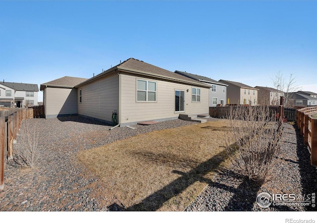 rear view of property featuring a residential view, a fenced backyard, and a lawn