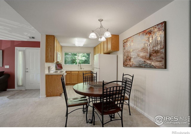 dining area with light colored carpet, sink, and a chandelier