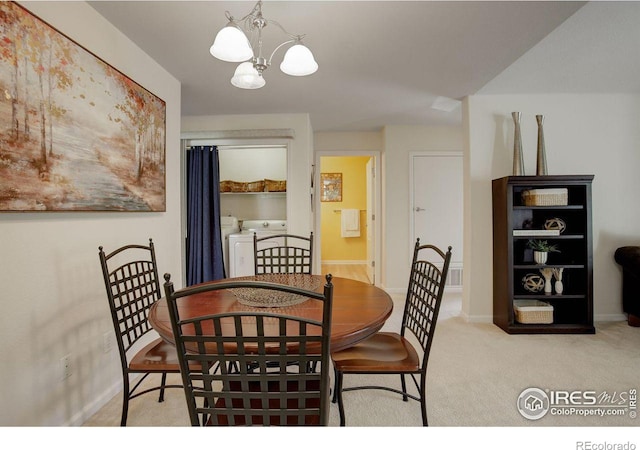 carpeted dining room featuring washing machine and dryer and a notable chandelier