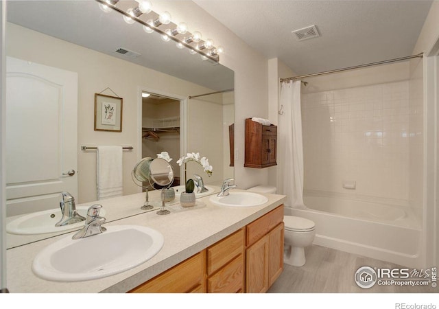 full bathroom with vanity, a textured ceiling, shower / tub combo with curtain, wood-type flooring, and toilet