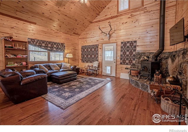 living room featuring a wood stove, wooden ceiling, high vaulted ceiling, wooden walls, and hardwood / wood-style flooring