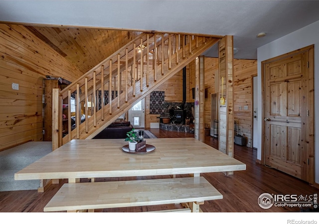 unfurnished dining area featuring a wood stove, dark wood-type flooring, and wooden walls