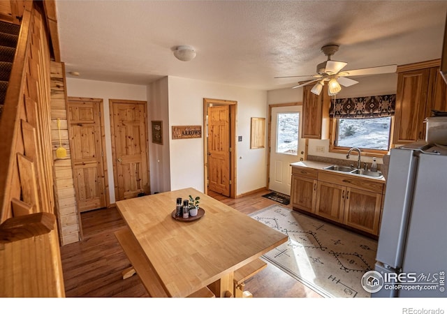 kitchen with ceiling fan, sink, white refrigerator, and light wood-type flooring