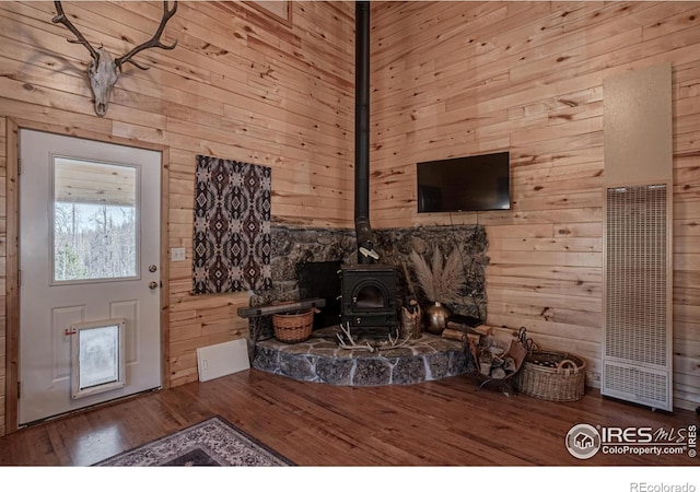 living room with hardwood / wood-style floors, a wood stove, and wood walls