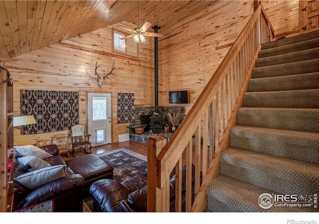 living room featuring a healthy amount of sunlight, a wood stove, wood walls, and wood ceiling