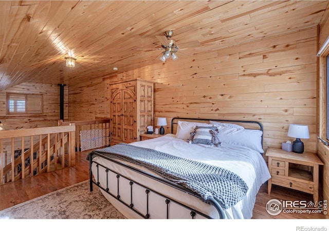 bedroom with wood-type flooring, wood ceiling, wooden walls, and vaulted ceiling