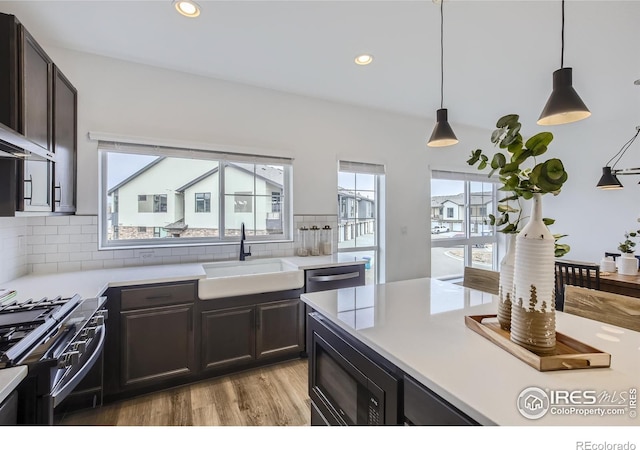 kitchen featuring high end range, black microwave, sink, pendant lighting, and plenty of natural light