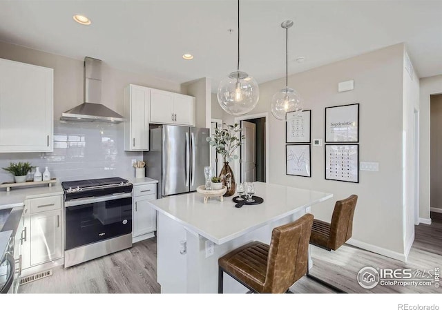 kitchen with a center island, white cabinets, wall chimney range hood, tasteful backsplash, and stainless steel appliances