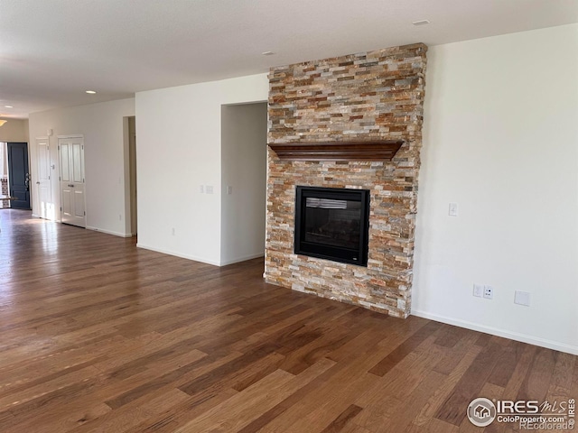unfurnished living room with baseboards, wood finished floors, and a fireplace