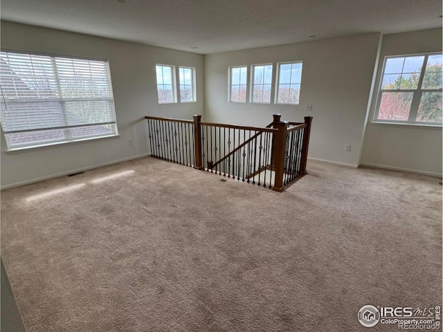 unfurnished room featuring carpet floors, visible vents, and baseboards
