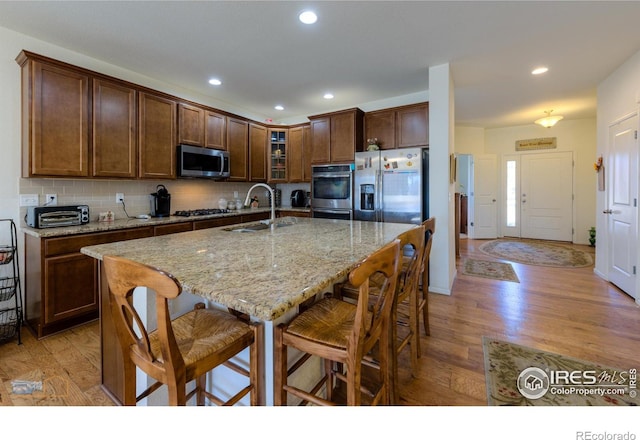 kitchen with stainless steel appliances, a kitchen breakfast bar, a sink, and glass insert cabinets