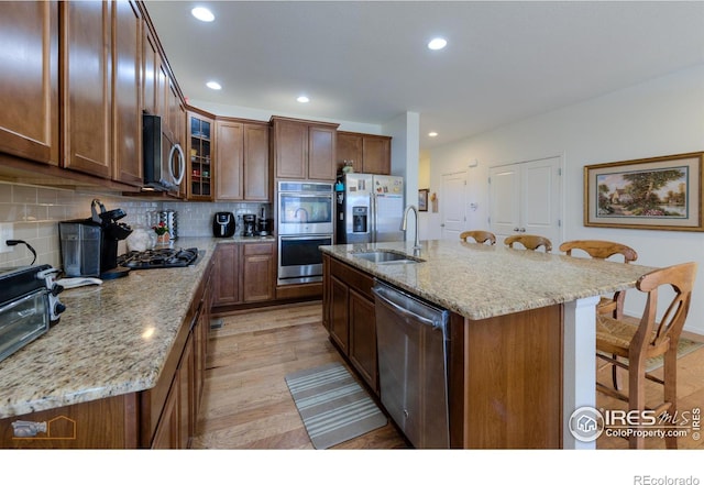 kitchen with a sink, decorative backsplash, stainless steel appliances, a kitchen bar, and recessed lighting