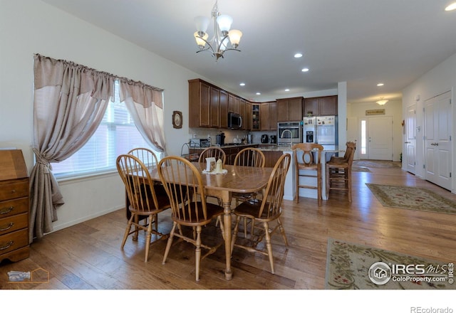 dining room featuring recessed lighting, light wood-style flooring, baseboards, and a notable chandelier