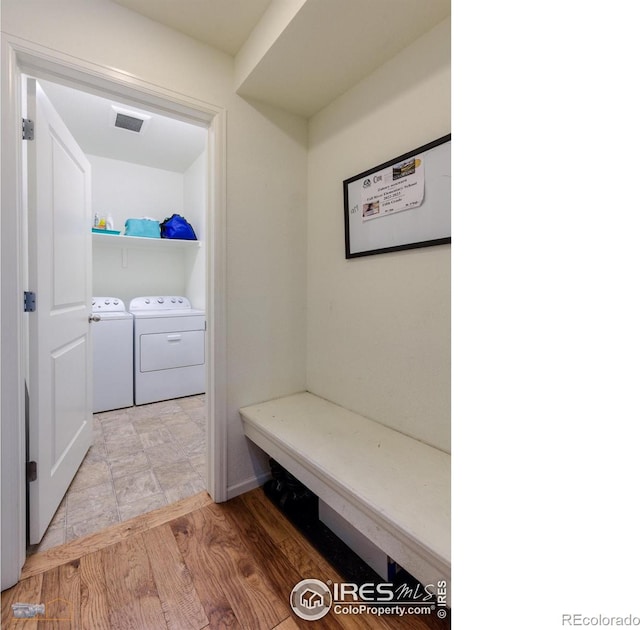 mudroom featuring washing machine and clothes dryer, visible vents, and light wood-type flooring