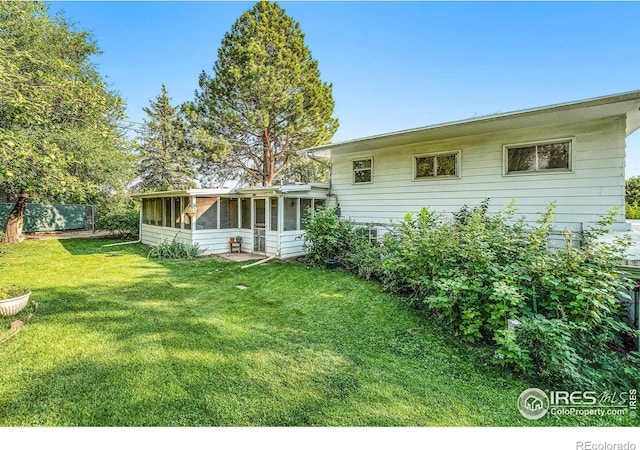 rear view of property with a sunroom and a lawn