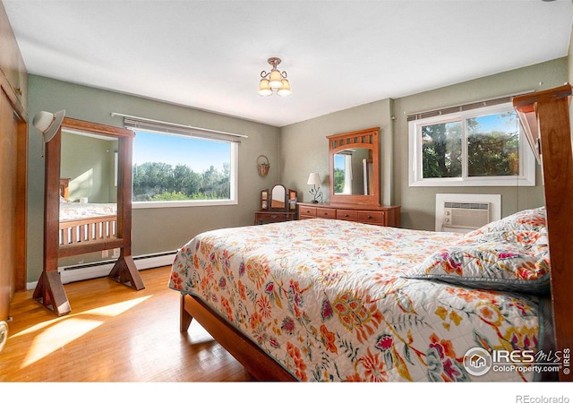 bedroom with a wall mounted AC, wood-type flooring, and a baseboard radiator