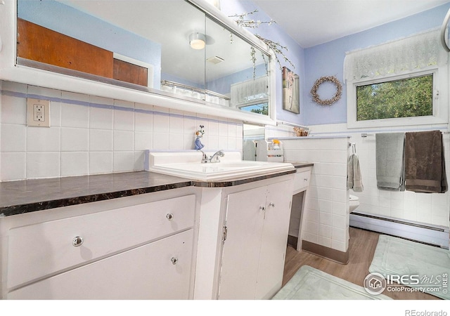 bathroom with a baseboard radiator, hardwood / wood-style floors, vanity, backsplash, and toilet