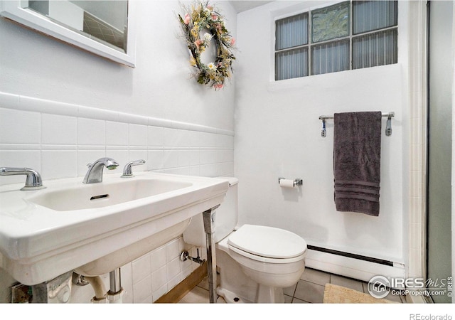 bathroom featuring a baseboard heating unit, toilet, tile patterned flooring, and sink