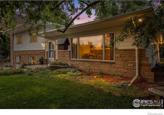 back house at dusk featuring a lawn