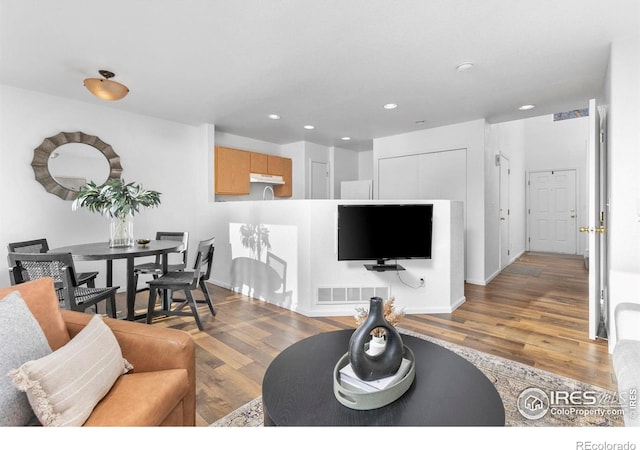 living area with recessed lighting, visible vents, and light wood finished floors