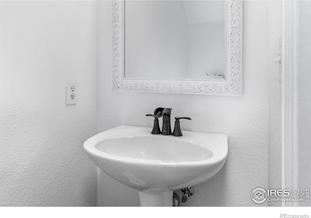 bathroom featuring a textured wall and a sink