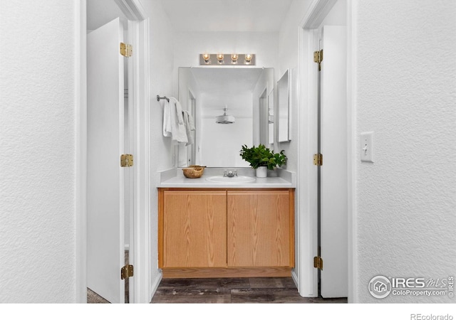 bathroom with a textured wall, wood finished floors, and vanity