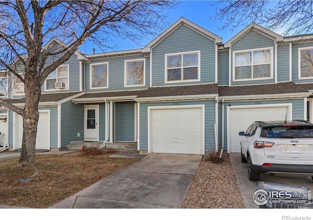 townhome / multi-family property with a garage, driveway, and a shingled roof