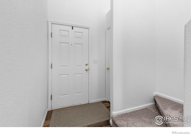 entryway featuring a textured wall and baseboards