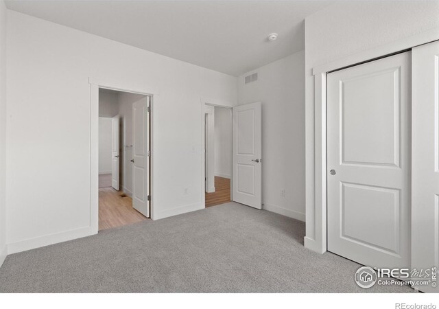 unfurnished bedroom featuring a closet and light colored carpet