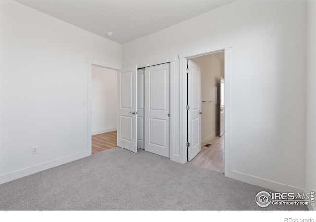 unfurnished bedroom featuring a closet and light colored carpet