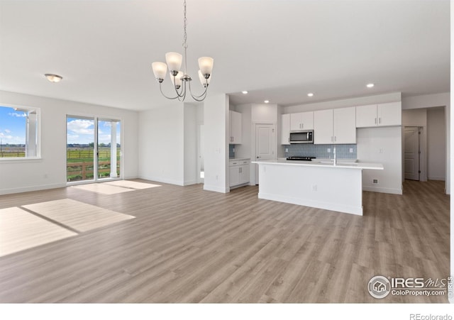 kitchen featuring white cabinetry, a center island with sink, decorative light fixtures, and an inviting chandelier