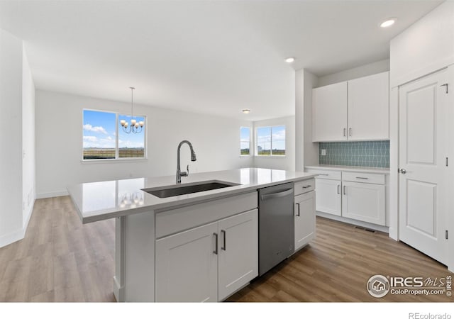 kitchen with stainless steel dishwasher, white cabinetry, and a kitchen island with sink