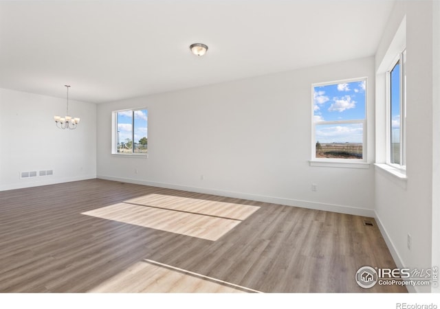 spare room featuring hardwood / wood-style flooring and a notable chandelier